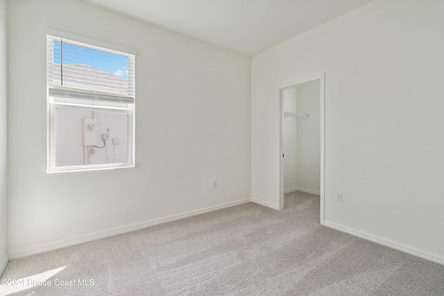 unfurnished bedroom featuring light carpet, a spacious closet, and a closet