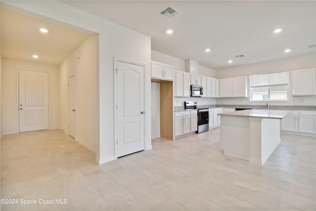 kitchen with white cabinetry, a center island, stainless steel appliances, and light stone counters