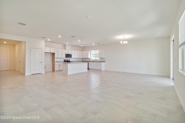 unfurnished living room with sink and a notable chandelier