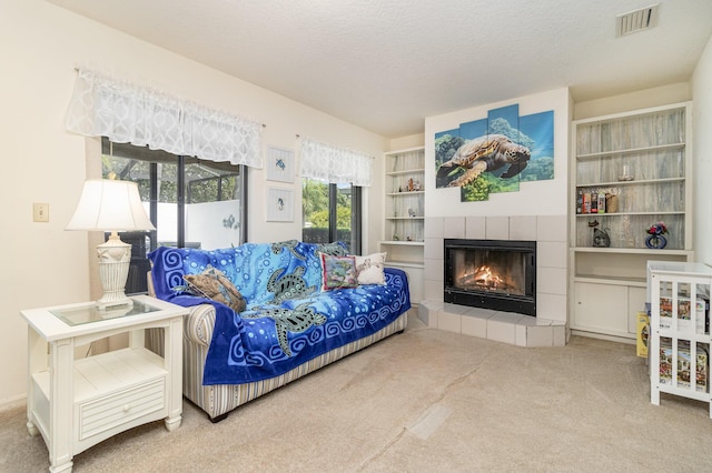 carpeted living room featuring a tiled fireplace and a textured ceiling