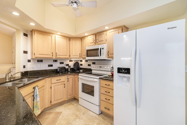 kitchen featuring sink, white appliances, a towering ceiling, dark stone counters, and light brown cabinets