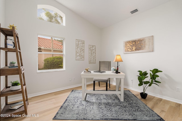 office space featuring lofted ceiling, a healthy amount of sunlight, and light wood-type flooring