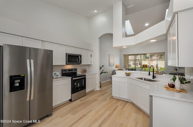 kitchen with white cabinets, high vaulted ceiling, light wood-type flooring, stainless steel appliances, and sink