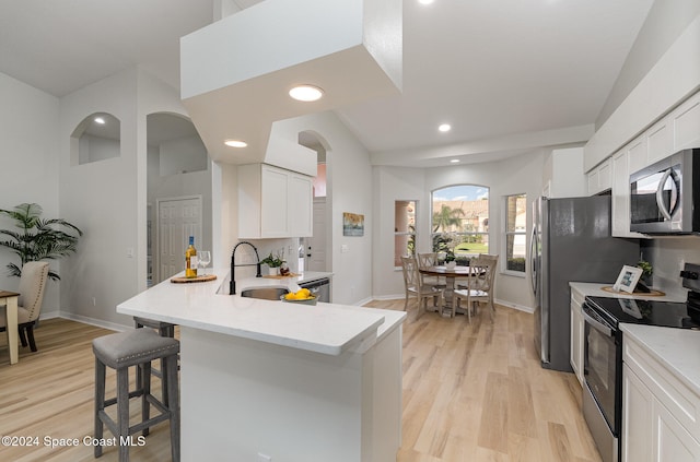 kitchen featuring a breakfast bar area, white cabinets, light hardwood / wood-style flooring, and stainless steel appliances