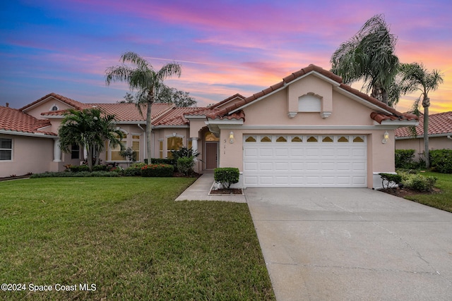 mediterranean / spanish-style home featuring a lawn and a garage