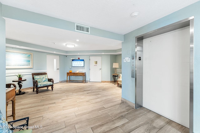 hallway with light hardwood / wood-style flooring and elevator