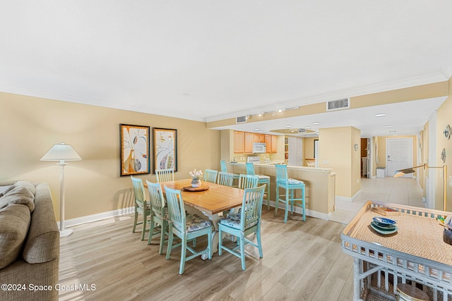 dining area with light hardwood / wood-style floors and ornamental molding