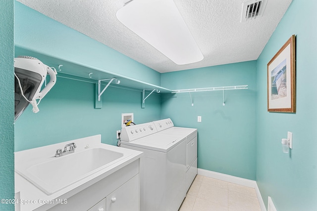 washroom featuring independent washer and dryer, a textured ceiling, light tile patterned floors, and sink