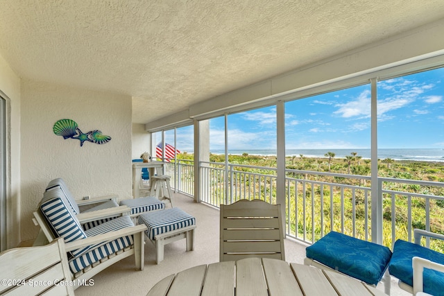 sunroom / solarium with a water view and a view of the beach