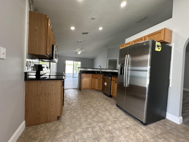 kitchen with kitchen peninsula, appliances with stainless steel finishes, a textured ceiling, vaulted ceiling, and sink