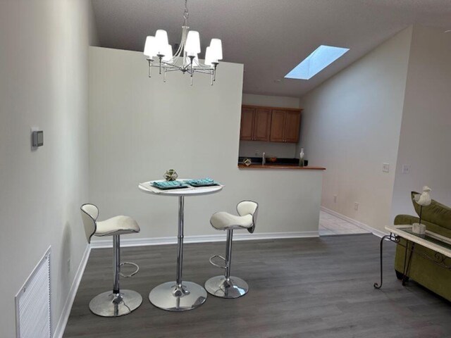 dining space with a skylight, wood-type flooring, and a chandelier