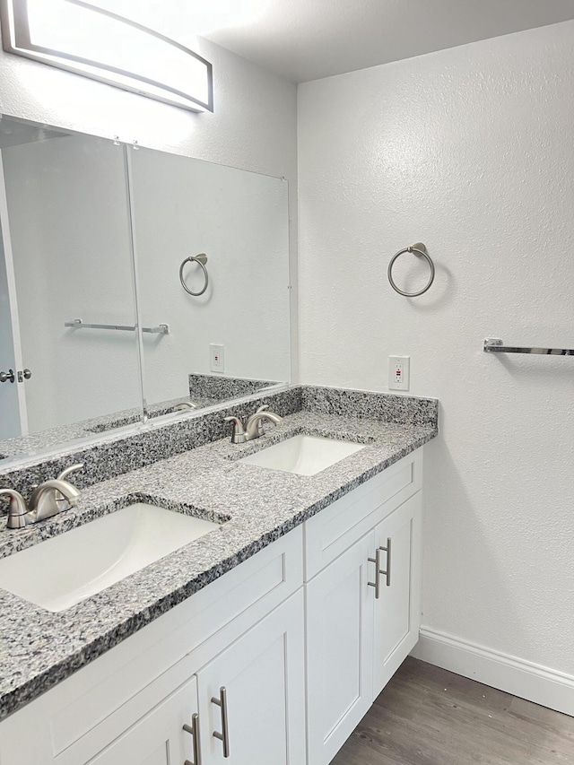 bathroom featuring hardwood / wood-style flooring, oversized vanity, and double sink