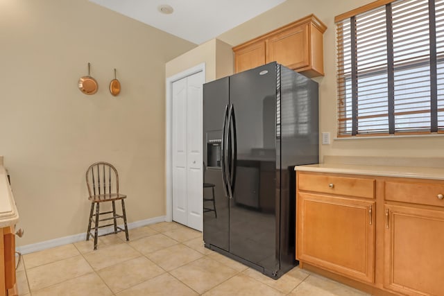 kitchen with black fridge with ice dispenser and light tile patterned floors