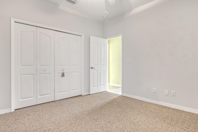 unfurnished bedroom featuring ceiling fan, a closet, and carpet