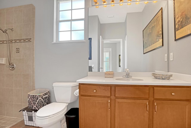 bathroom with tile patterned flooring, vanity, toilet, and tiled shower