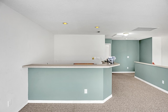 kitchen with a textured ceiling, kitchen peninsula, and carpet floors