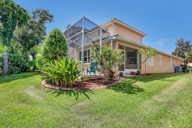 rear view of house featuring glass enclosure, central air condition unit, and a yard