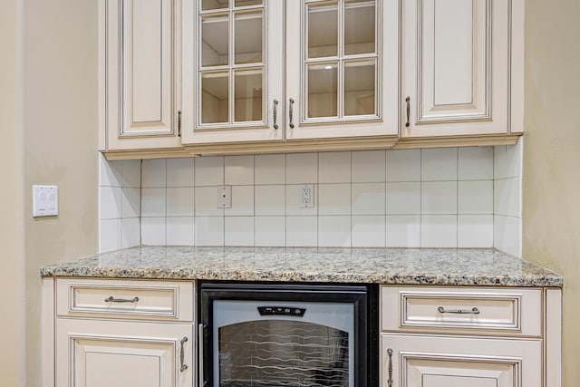 interior space with beverage cooler, light stone countertops, cream cabinets, and backsplash