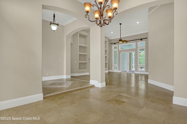 interior space featuring built in shelves, ornamental molding, and ceiling fan with notable chandelier