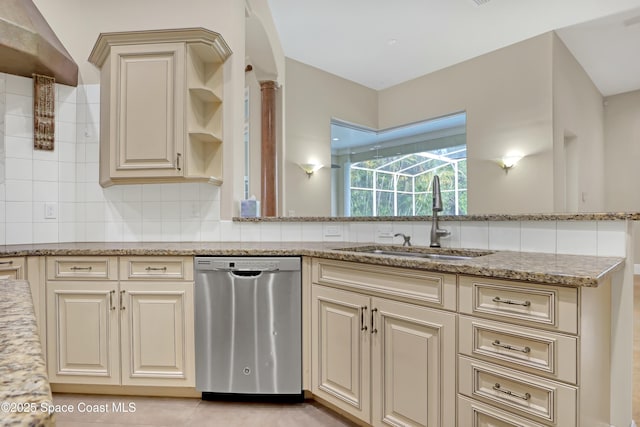 kitchen featuring sink, light stone counters, dishwasher, cream cabinets, and backsplash