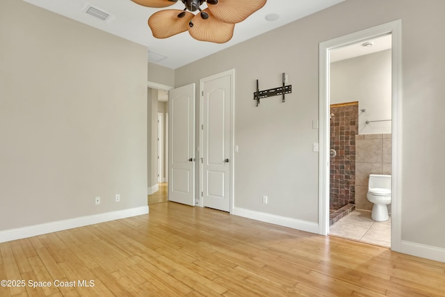 unfurnished bedroom with tile walls, connected bathroom, light hardwood / wood-style floors, and ceiling fan