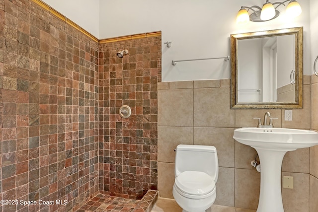 bathroom featuring tile walls, toilet, and tiled shower