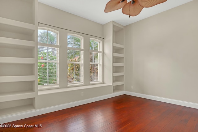 spare room with built in shelves, ceiling fan, and wood-type flooring