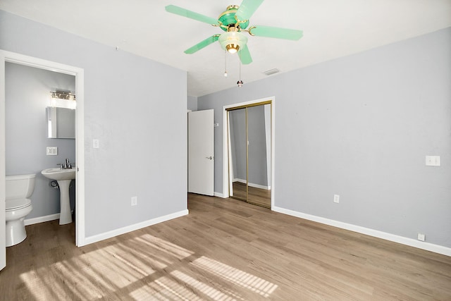 unfurnished bedroom with ceiling fan, ensuite bath, light hardwood / wood-style floors, and a closet