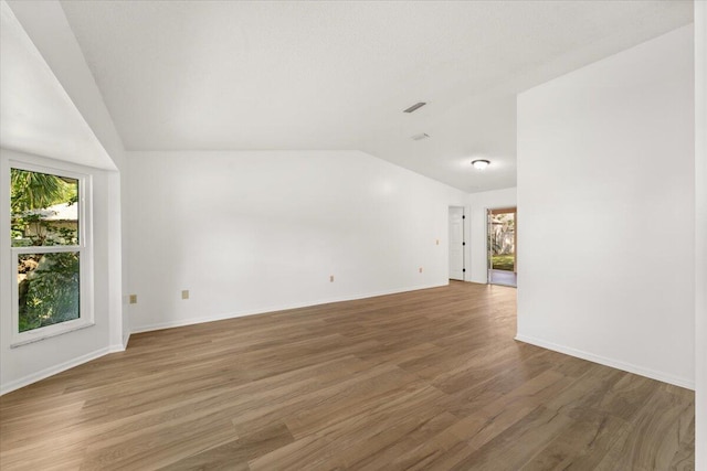 unfurnished room with hardwood / wood-style floors and lofted ceiling