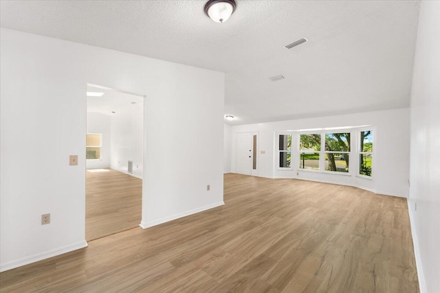 unfurnished living room with light hardwood / wood-style floors and a textured ceiling