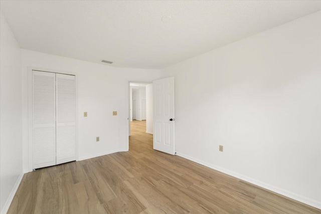 unfurnished bedroom featuring light hardwood / wood-style floors and a closet