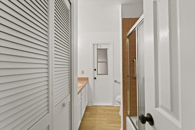 bathroom with vanity, hardwood / wood-style flooring, toilet, and an enclosed shower