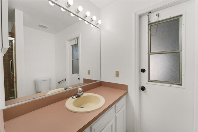 bathroom featuring walk in shower, vanity, and toilet