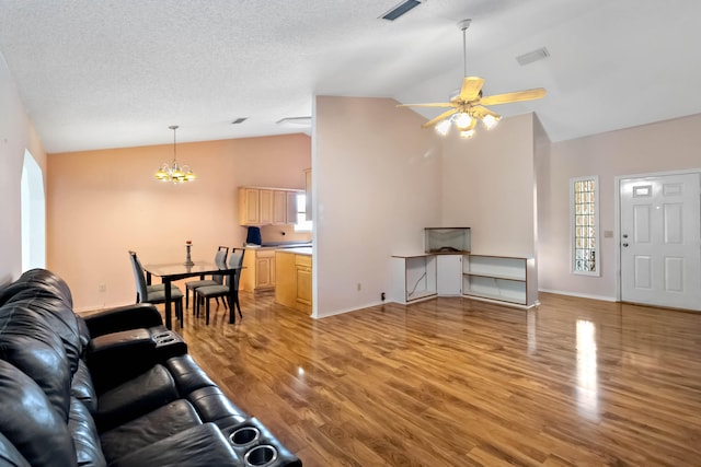 living room featuring light hardwood / wood-style floors, a textured ceiling, lofted ceiling, and ceiling fan with notable chandelier