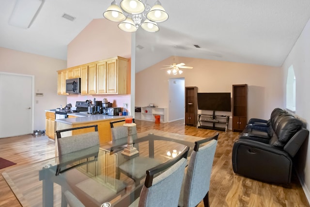 dining space featuring high vaulted ceiling, light hardwood / wood-style floors, and ceiling fan with notable chandelier