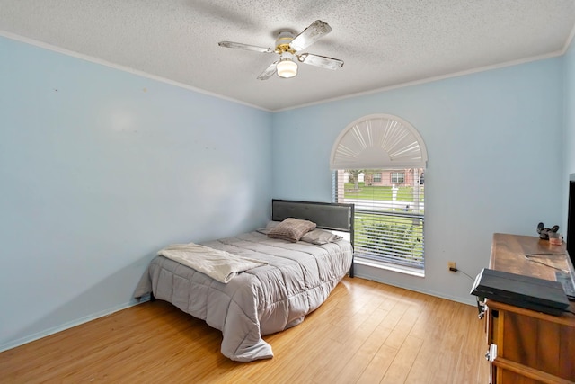 bedroom with ceiling fan, a textured ceiling, light wood-type flooring, and ornamental molding