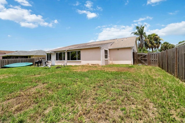 1632 Cains Ave NW, Palm Bay, FL 32907 - rear view of property featuring a fenced backyard, a gate, stucco siding, and a yard
