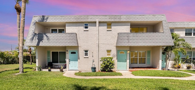 view of front facade featuring a balcony and a lawn