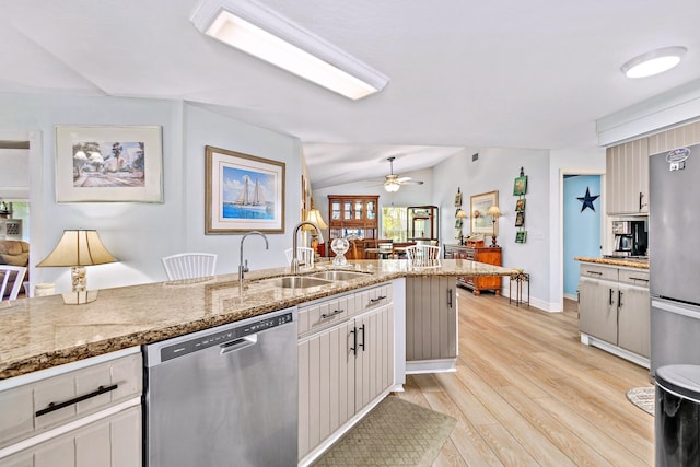 kitchen with light hardwood / wood-style floors, appliances with stainless steel finishes, sink, light stone counters, and lofted ceiling