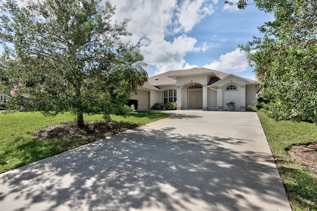 mediterranean / spanish house with a garage and a front lawn