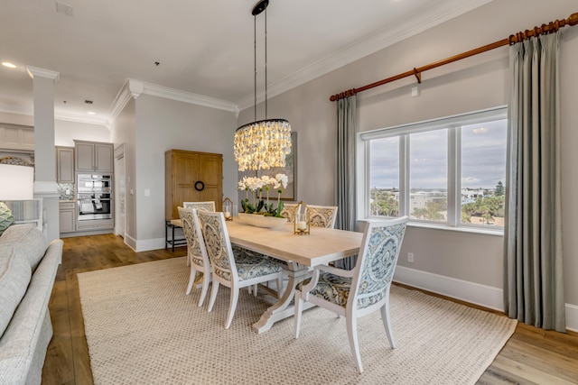 dining room featuring ornamental molding, light wood-type flooring, and a chandelier