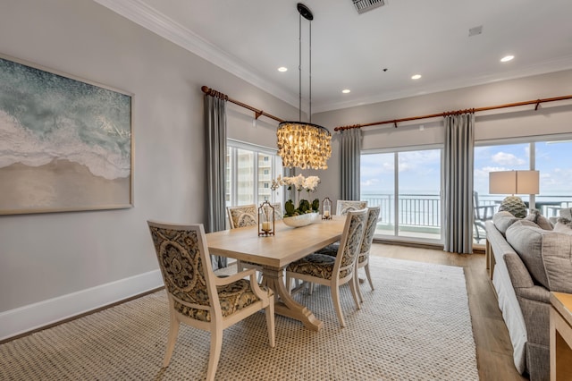 dining space with ornamental molding, hardwood / wood-style floors, and a chandelier