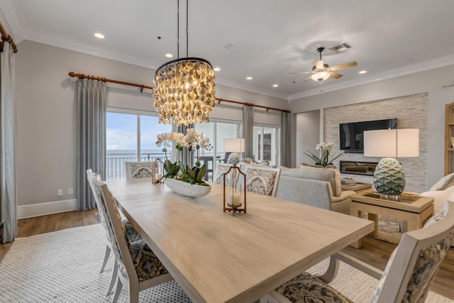 dining room with light hardwood / wood-style floors, ornamental molding, and ceiling fan with notable chandelier