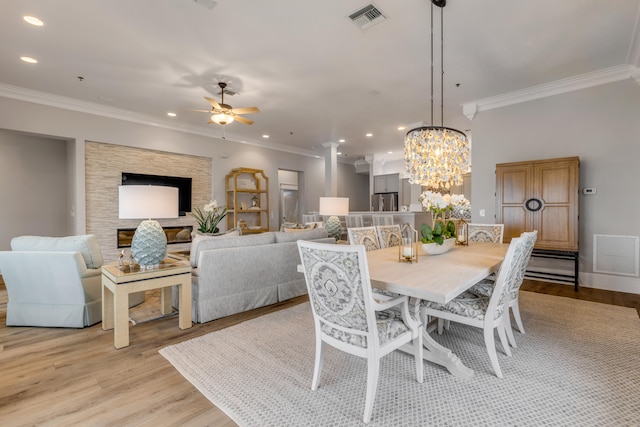 dining space with ornamental molding, light wood-type flooring, and ceiling fan with notable chandelier