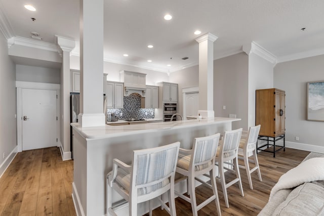 kitchen featuring a kitchen breakfast bar, light hardwood / wood-style floors, kitchen peninsula, and backsplash