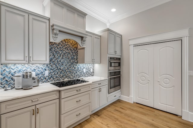 kitchen featuring light hardwood / wood-style floors, crown molding, black electric stovetop, stainless steel double oven, and tasteful backsplash