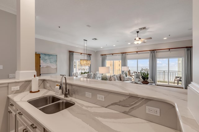 kitchen featuring hanging light fixtures, ceiling fan, white cabinetry, light stone countertops, and sink