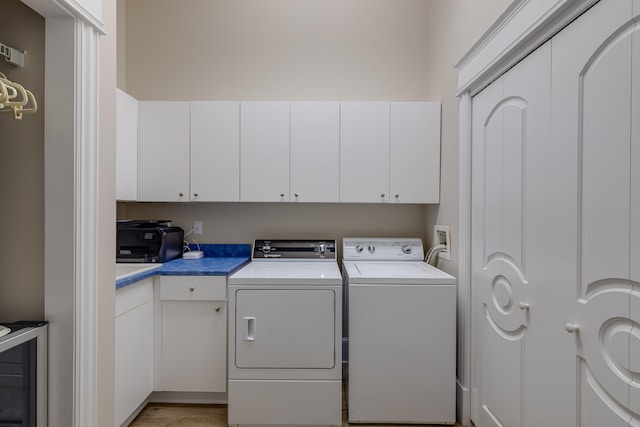 laundry area featuring cabinets, light wood-type flooring, washer hookup, washing machine and clothes dryer, and wine cooler