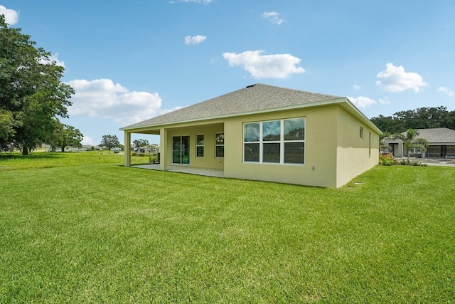 back of house featuring a patio, a lawn, roof with shingles, and stucco siding