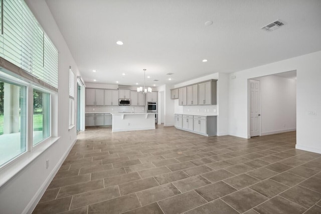 unfurnished living room featuring an inviting chandelier and dark tile patterned floors